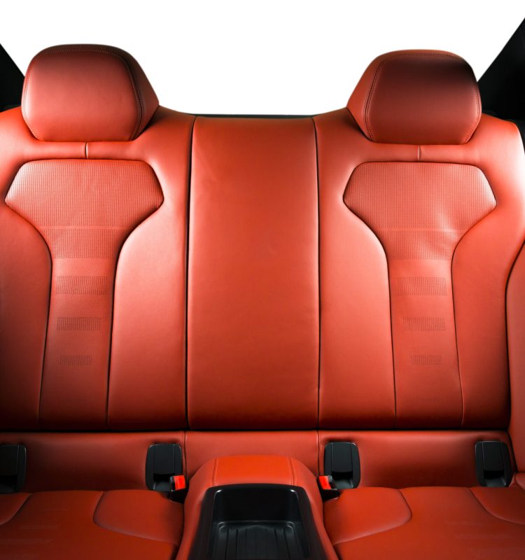 Back passenger seats in modern luxury car, frontal view, red perforated leather with stitching